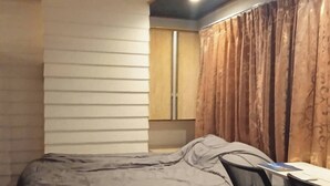 A compact bedroom with a bed, a desk, and a chair. - Spacious City-view Apartment With Modern Amenities in Krung Thep (Bangkok)
