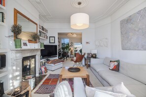 Ein geräumiges Wohnzimmer mit Kamin, Fernseher und großem Fenster.