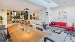 Un espace de vie moderne comprenant un coin repas, un canapé rouge et une cuisine en arrière-plan.