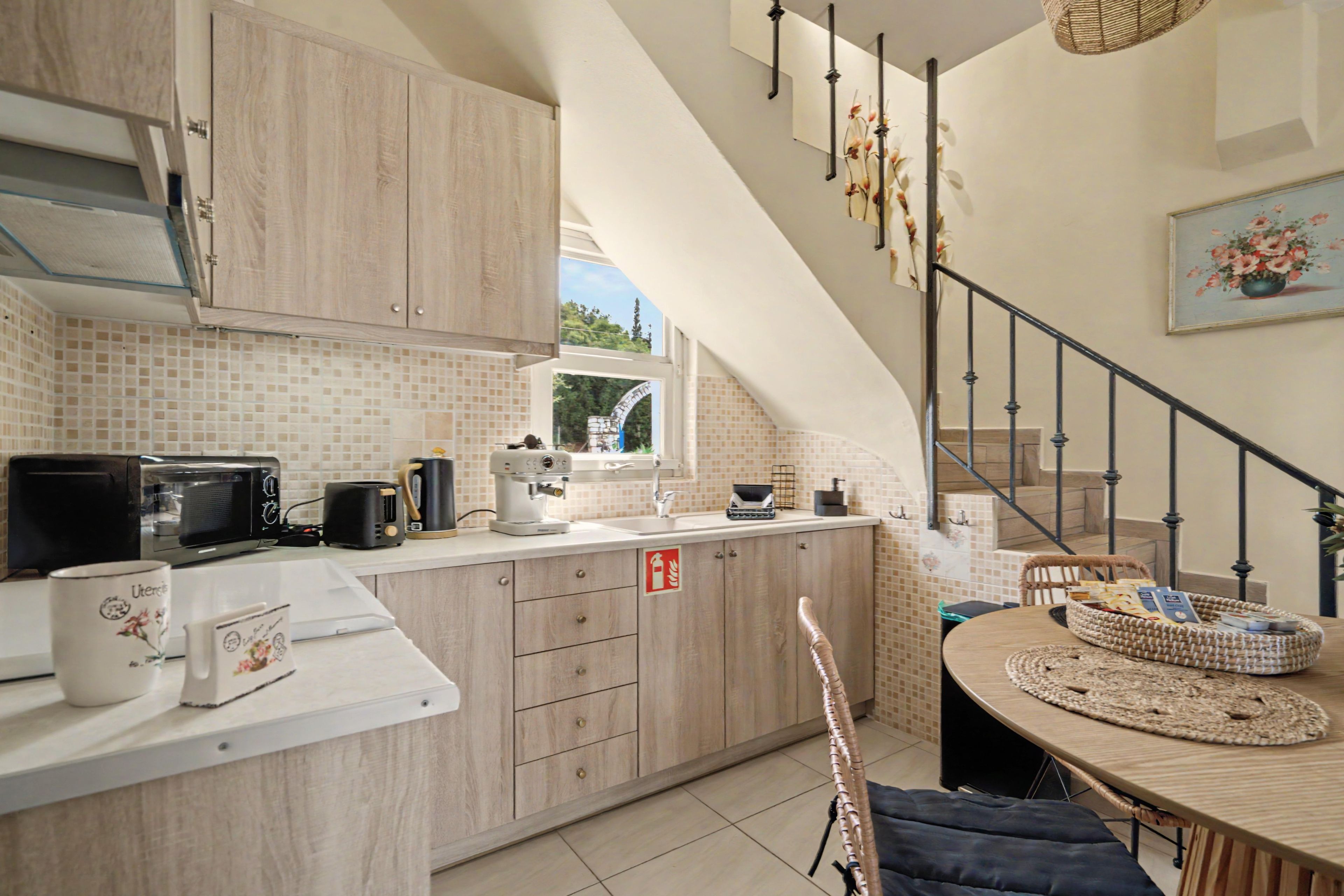 Una cucina con mobili in legno, un piano di lavoro bianco e un'area pranzo con tavolo e sedie.