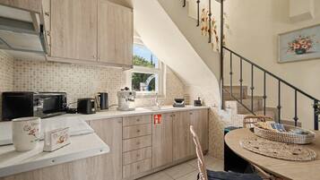 Una cucina con mobili in legno, un piano di lavoro bianco e un'area pranzo con tavolo e sedie.