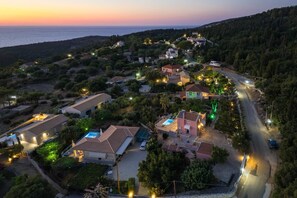Una zona residencial costera con casas, una piscina y una carretera.