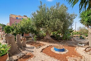 Een tuin met een grote boom, stenen paden en een gebouw op de achtergrond.