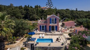 Una casa de dos pisos con piscina, mobiliario exterior y vistas al bosque circundante.