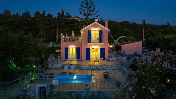 Una casa de dos pisos con balcón, piscina y terraza de piedra.