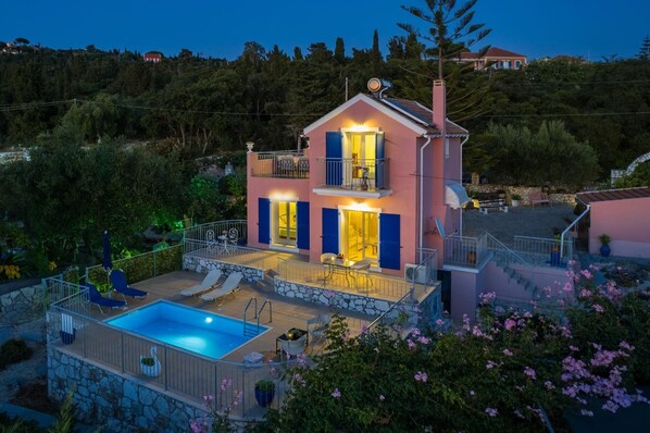 A two-story house with a swimming pool, outdoor seating, and a balcony.