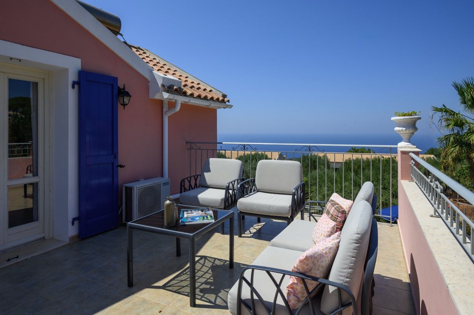 A balcony with outdoor furniture, a door, and a view of the sea.