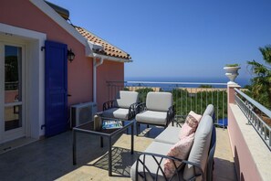 Un balcon avec des meubles d’extérieur, une porte et une vue sur la mer.