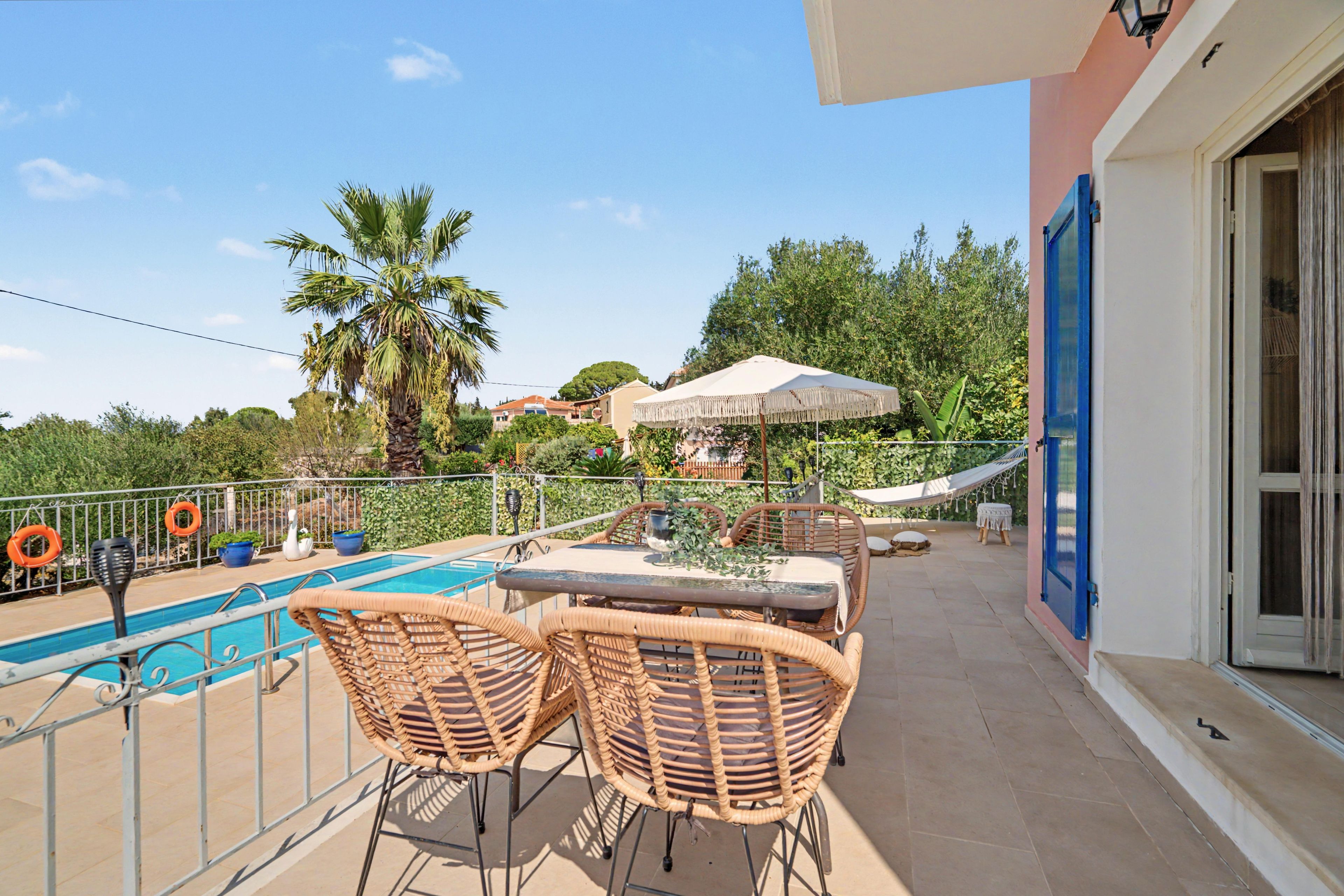 A balcony with a pool, wicker furniture, and a view of the surrounding area.