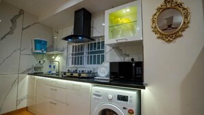 A compact kitchen with a built-in washing machine, a microwave, and a gas stove. - AS Inn (Kanayannur)