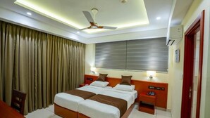 A hotel room with a large bed, bedside tables, a desk, and a ceiling fan. - AS Inn (Kanayannur)