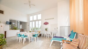 Un salon lumineux et spacieux, comprenant une table à manger, des chaises, un canapé et un téléviseur.