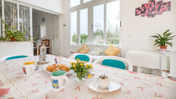 Un coin repas avec une table mise pour le petit-déjeuner, comprenant des viennoiseries et des fleurs.
