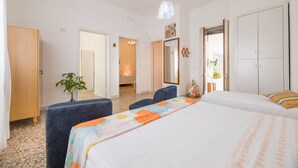 Une chambre d’hôtel avec un grand lit, un bureau, une chaise, une plante et une armoire.