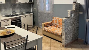 A compact kitchen with a dining area, including a table, chairs, and a sofa. - Casa Ninì, charming accommodation in the center (Campofelice di Roccella)