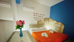 A bedroom with a bed, a nightstand, a vase with flowers, and a motivational quote on the wall. - Casa Ninì, charming accommodation in the center (Campofelice di Roccella)