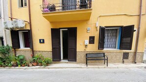 A yellow building with a balcony, a bench outside, and a manhole cover on the pavement. - Casa Ninì, charming accommodation in the center (Campofelice di Roccella)