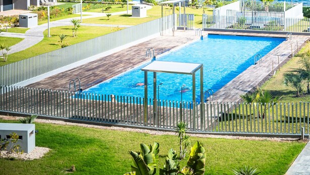 Un hôtel moderne doté d’une piscine, de palmiers et offrant une vue sur l’océan.