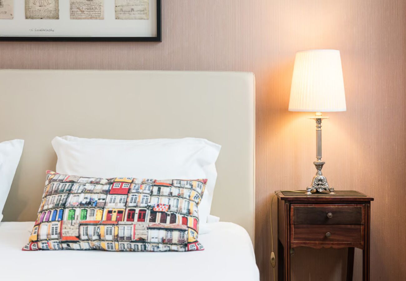 A neatly made bed with a colorful pillow and a bedside table with a lamp.