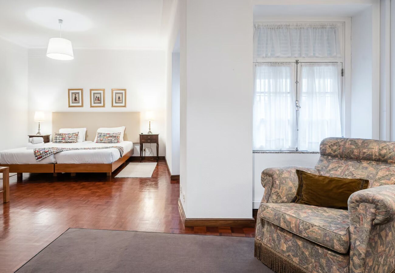 A bedroom with a bed, bedside tables, a nightstand, and a window with curtains.