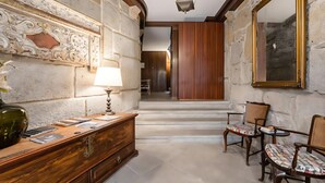 A hallway with a wooden desk, a lamp, and two chairs.