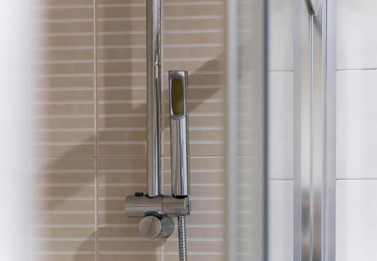 A chrome showerhead mounted on a wall with a horizontal bar.