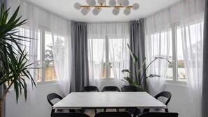 Een moderne eetkamer met een rechthoekige tafel, zwarte stoelen en een kroonluchter.