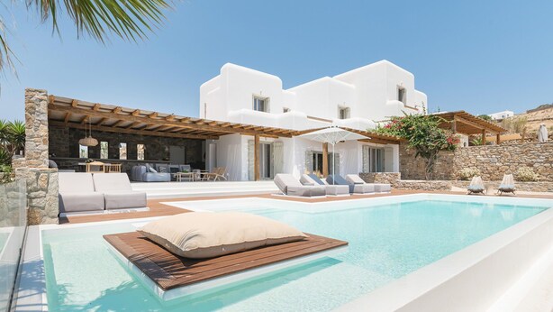 A modern villa with a pool, outdoor seating, and a stone wall. - Villa Demetra with pool - My Rental Homes (Mykonos)