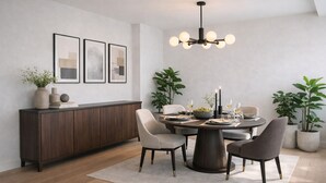 A modern dining area with a round table, chairs, a dark wooden cabinet, and framed artwork on the wall. - Sophisticated 3-Bed Residence for 6 | Urban Calm (London)