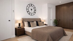 A bedroom with a large bed, a wall clock, a wardrobe, and a bedside table with lamps. - Sophisticated 3-Bed Residence for 6 | Urban Calm (London)