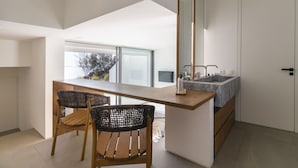 Eine moderne Küche mit Holztisch und -stühlen, einem großen Fenster und einer eingebauten Spüle.