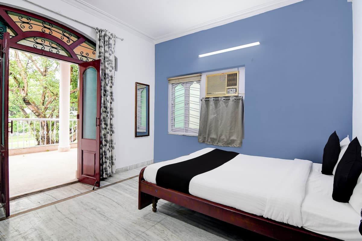 A bedroom with a bed, a window, a door, and a view of greenery outside.