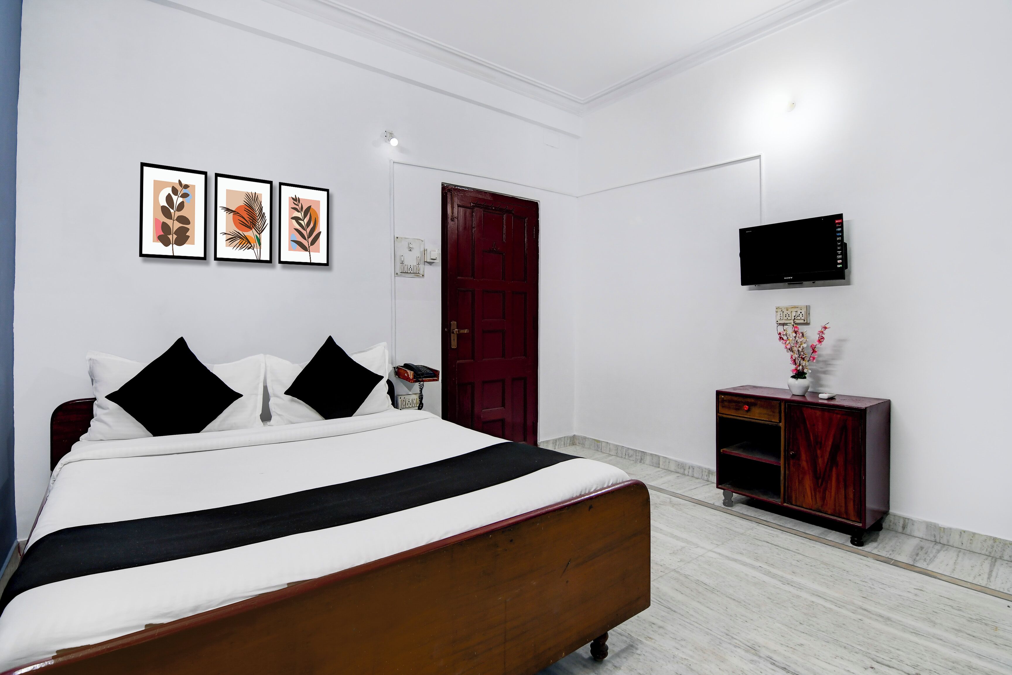 Quarto bem arrumado com uma cama, um armário de madeira, uma televisão e quadros na parede.