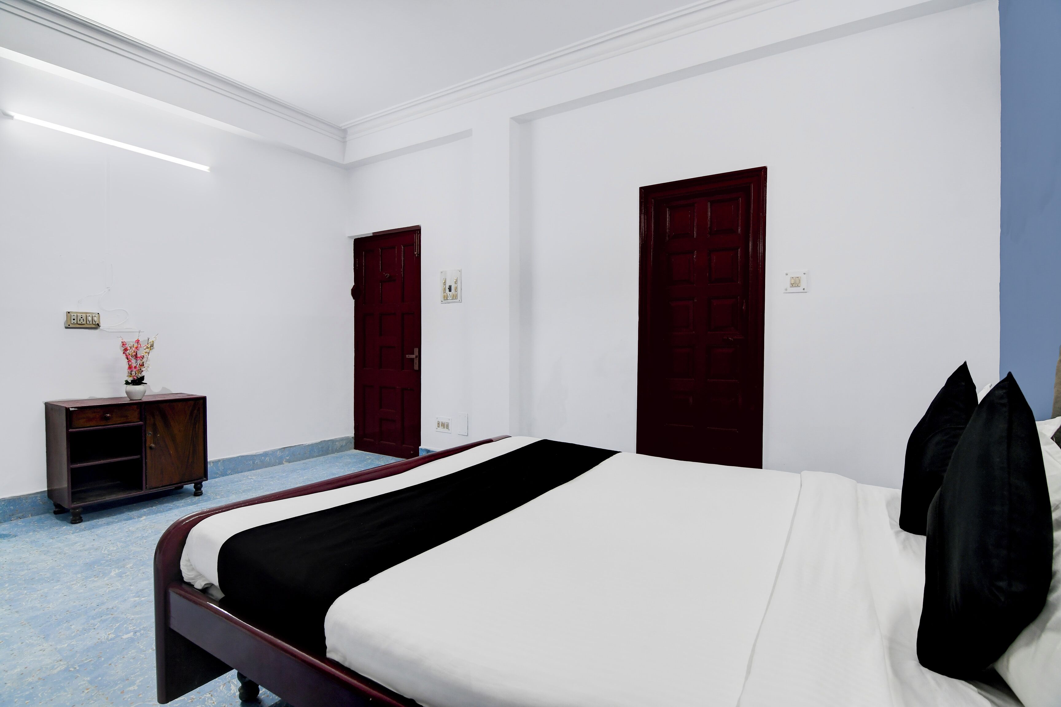 Un dormitorio con cama, mesita de noche, cómoda y dos puertas.