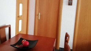Ruokailuhuoneessa on puinen pöytä, tuoleja ja seinällä oleva kello.