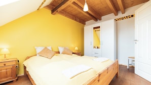 Un dormitorio con cama de madera, mesita de noche, armario y espejo.