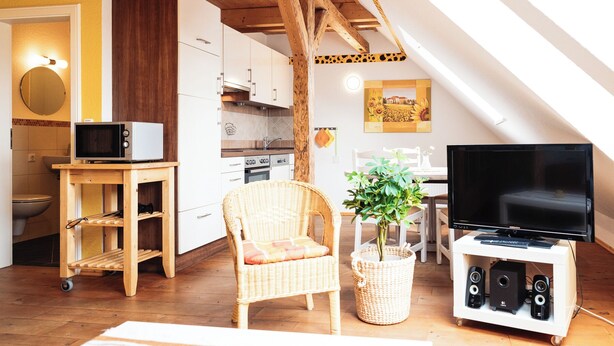 Un espacio habitable compacto con kitchenette, comedor y televisor.