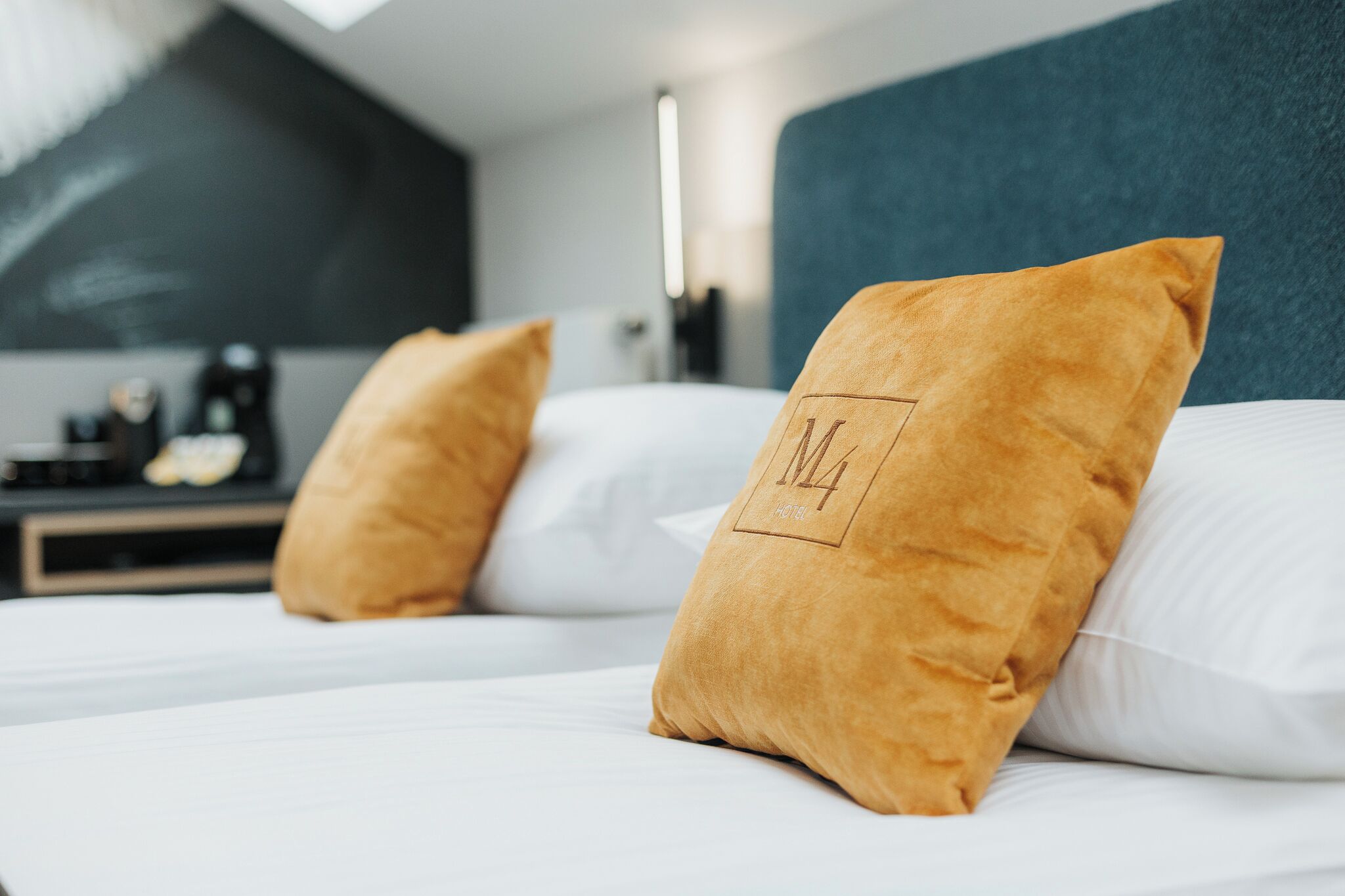 Ein Bett mit weißen Laken und zwei Kissen, eines mit einem Logo.