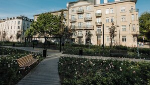 Un camino que lleva a un edificio con varios balcones, rodeado por un jardín con tulipanes y bancos.