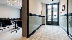 Un vestíbulo de hotel con mostrador de recepción, zona de estar y entrada por puerta de vidrio.