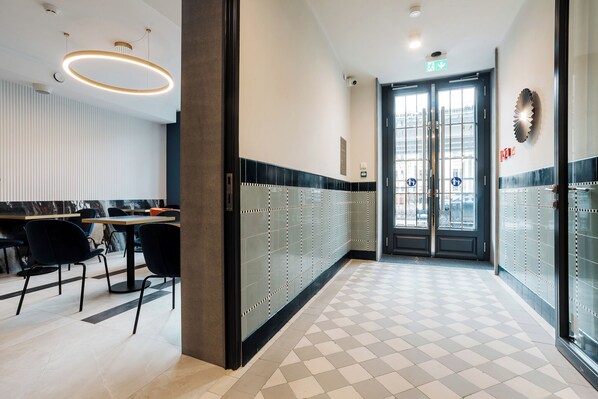 Un vestíbulo de hotel con mostrador de recepción, zona de estar y entrada por puerta de vidrio.