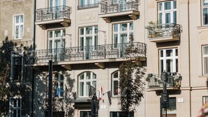 Un edificio de varios pisos con balcones, ventanas amplias y una bandera.