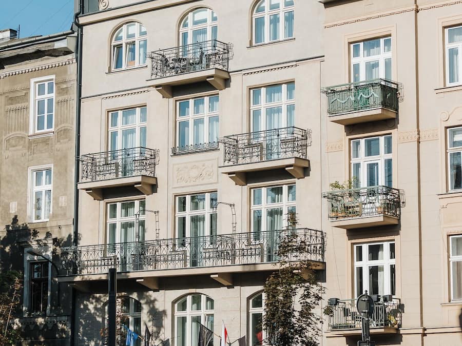 A multi-story building with balconies, large windows, and a flag.