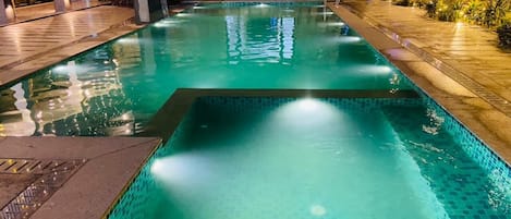 A swimming pool with a tiled edge, a stone wall, and a waterfall feature.