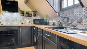 Una cocina con microondas, horno, lavavajillas y un perchero.