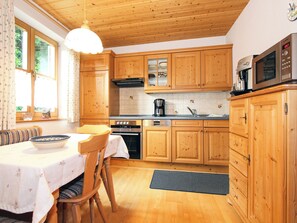 Eine Küche mit Holzausstattung, einem Herd, einer Mikrowelle und einem Essbereich mit Tisch und Stühlen.