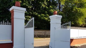 Una entrada cerrada con valla blanca y pilares de ladrillo.