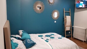 Un dormitorio con cama, televisor y adornos en la pared.