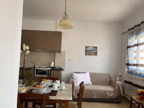 A compact living space with a kitchenette, dining area, and a sofa. - Lunar Melody Apartments Near the Beach Karpathos (Karpathos)