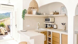 A modern kitchen with a white countertop, a hanging light fixture, a microwave, and a sink. - Terraza Azul - Penthouse with sea view by Interhome (Alcocéber/Alcossebre)